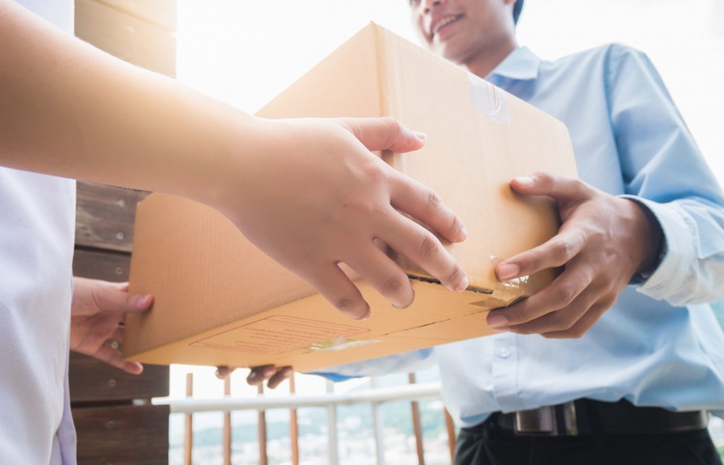 Hand of asia woman are receive a box from delivery man in delivery service concept.